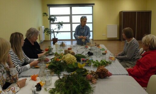 Grupa Pań siedząca przy stole i wykonująca swoje prace związane z tematem jesieni