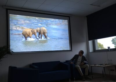 Podróżnik Piotr Kowalczyk omawia slajd z kąpiącymi się słoniątkami